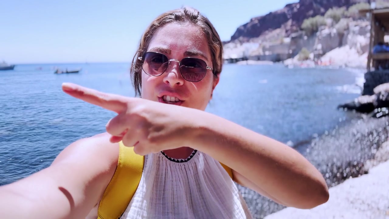 Donna influencer che fa vlogging alla spiaggia rossa a Santorini, Grecia