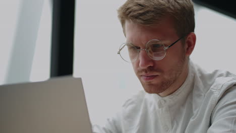 tired and frustrated man is reading and watching display of laptop in office or home closeup portrait