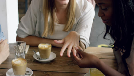 mujer hermosa mostrando anillo de compromiso a amigos en el plan de boda de café