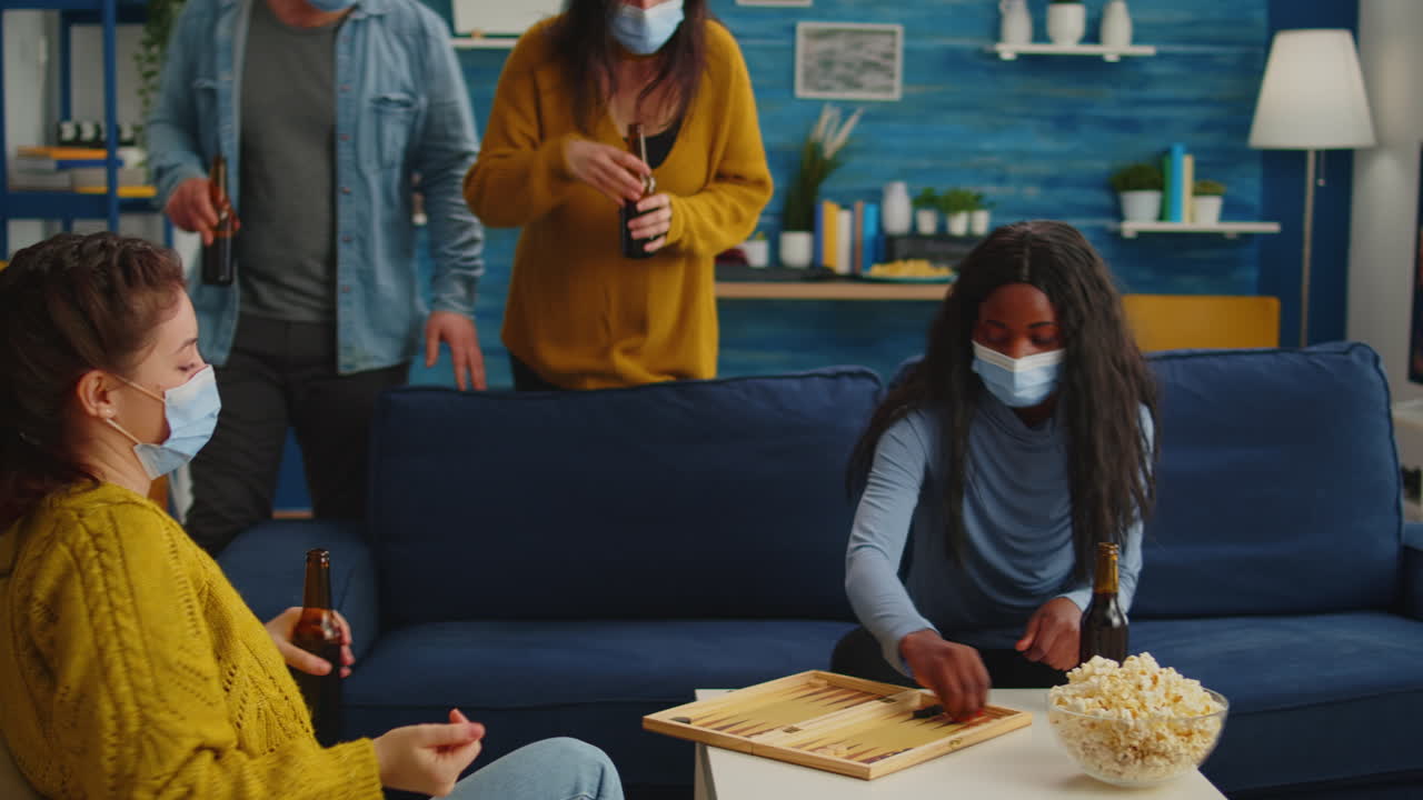 Multiethnical women playing backgammon wearing face mask