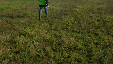 male engineer walking on the grass towards the two cellular towers, tilting shot revealing