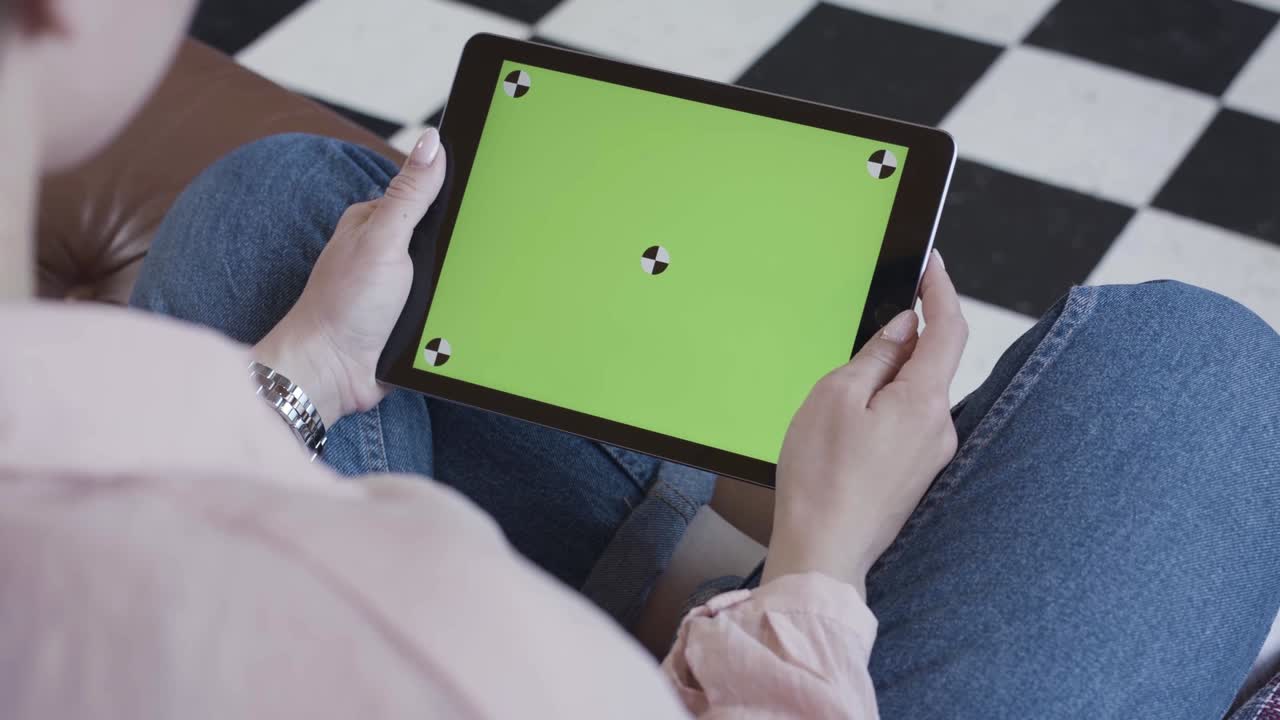 mujer sosteniendo una tableta con una pantalla verde