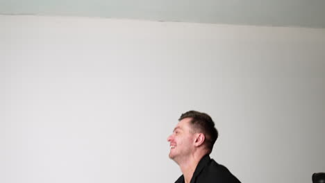 smiling caucasian man tossing his cute little baby. strong father holding his son up on one hand. white backdrop.