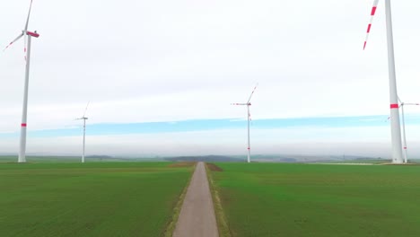 a road in green fields with towering wind turbines