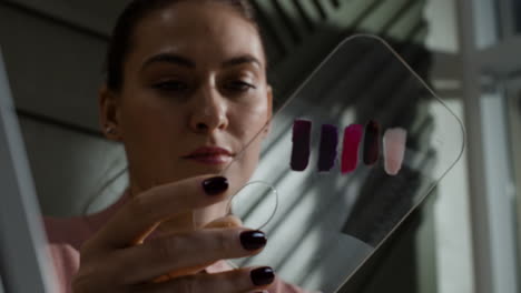 woman holding a lipstick and nail polish swatch palette