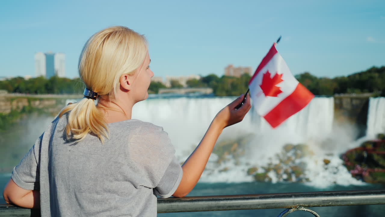 Donna che sventola la bandiera canadese alle Cascate del Niagara