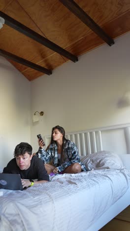 couple relaxing in bedroom with technology