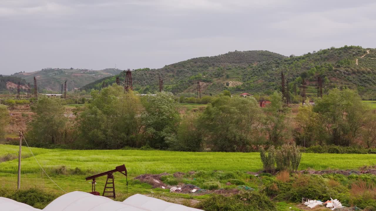Scenic view of oil field near Berat, Kucova, green landscape, cloudy sky