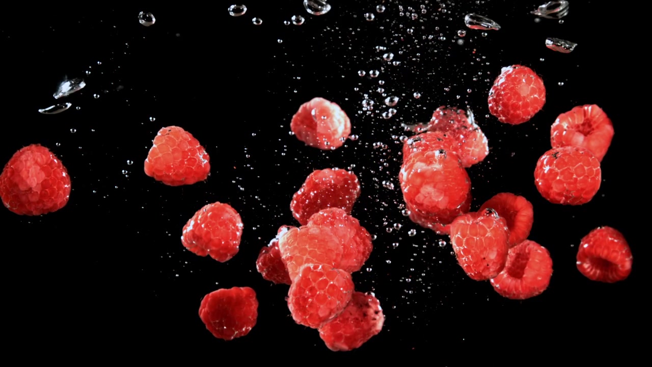 Fresh red raspberries floating in water with bubbles