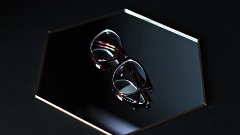 brown tortoiseshell rounded prescription glasses showcased in a modern contemporary way on a hexagonal mirror with a black backdrop