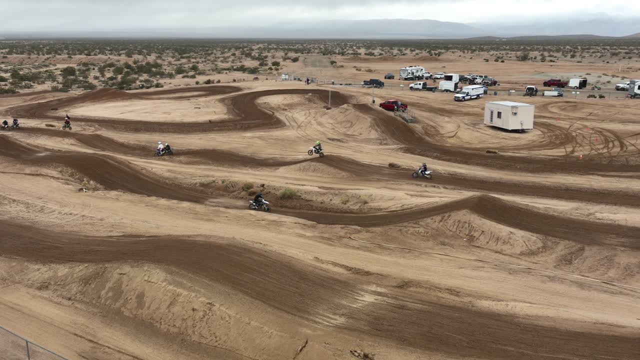 느린 동작으로 드론에서 본 것처럼 오프로드 경마장에서 장거리 점프하는 오토바이