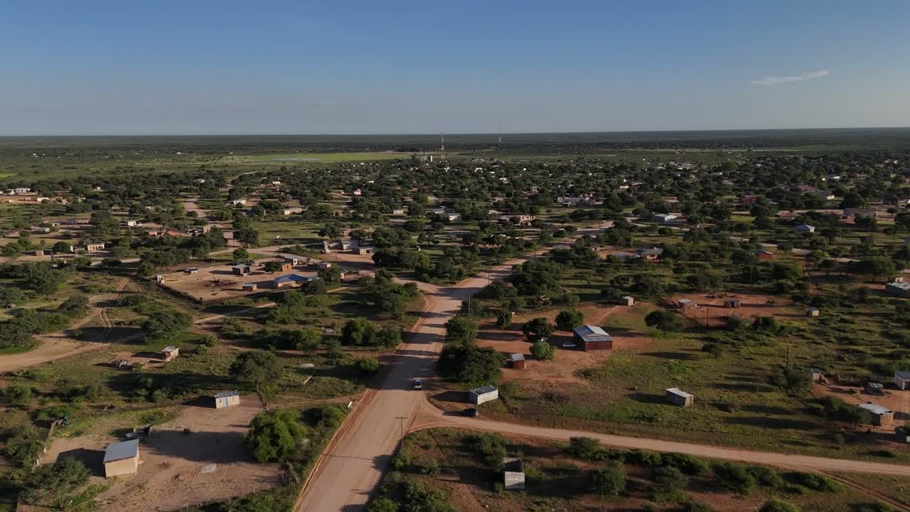 RIPRESA AEREA DI EDIFICI DI UN VILLAGGIO, STRADE E VEGETAZIONE CON UN CIELO AZZURRO LIMPIDO