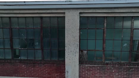 broken glass windows in worn out factory warehouse building