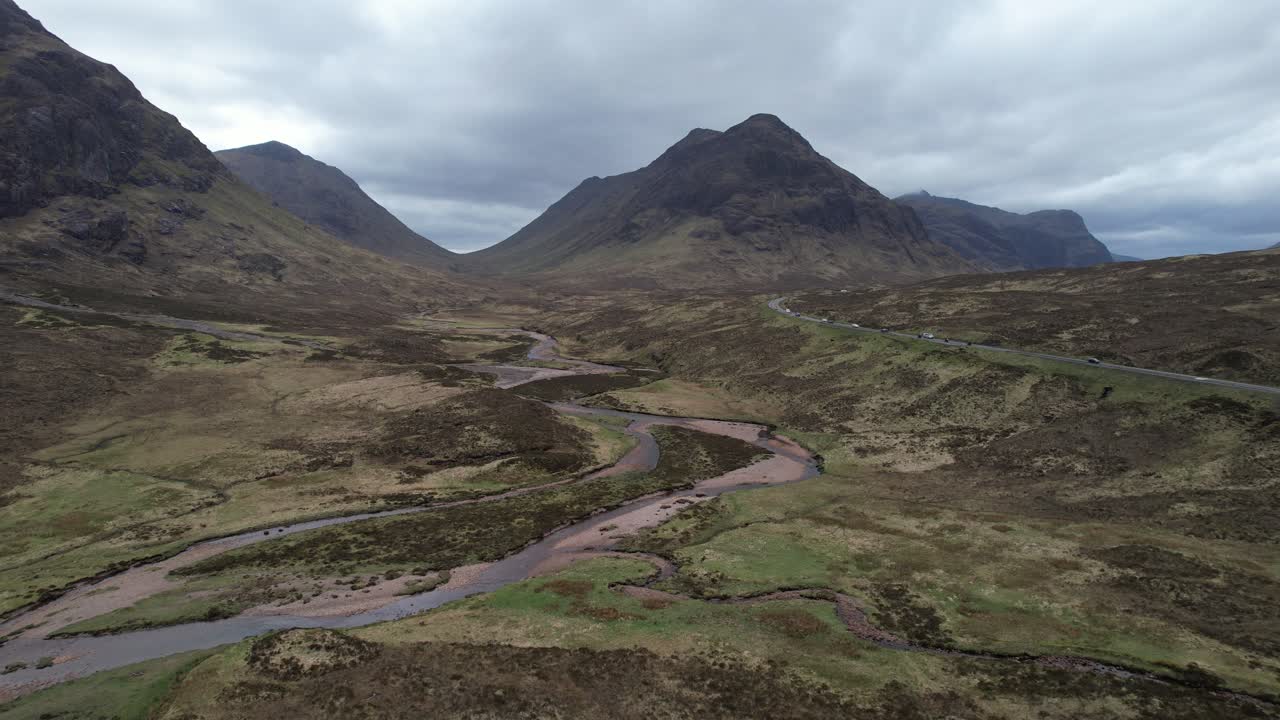 Epic view of Glencoe valley and cars driving in the Scottish Highlands