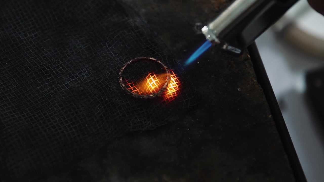 Ringmaker gebruikt een soldeerbrander om een ring te vervaardigen. Sieradenproductie