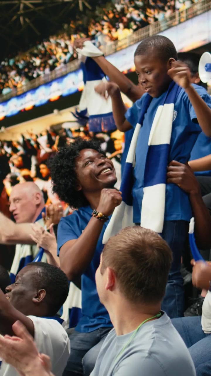 Video vertical. Diversos aficionados de fútbol del equipo azul animando en las gradas abarrotadas del estadio.