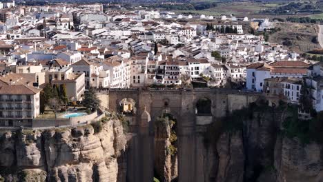 puente nuevo, a bridge connecting two sides of a deep gorge in ronda, spain, with white buildings covering the landscape, offering a breathtaking aerial perspective
