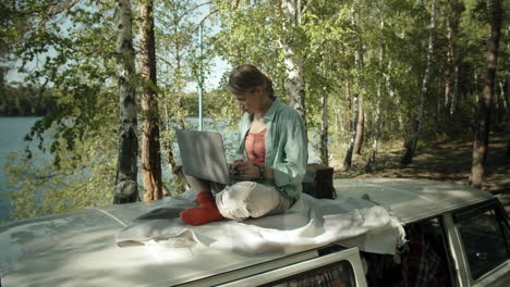 woman working on laptop on roof of camper van