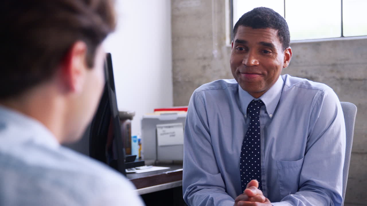 Mixed race manager speaking to young man at job interview