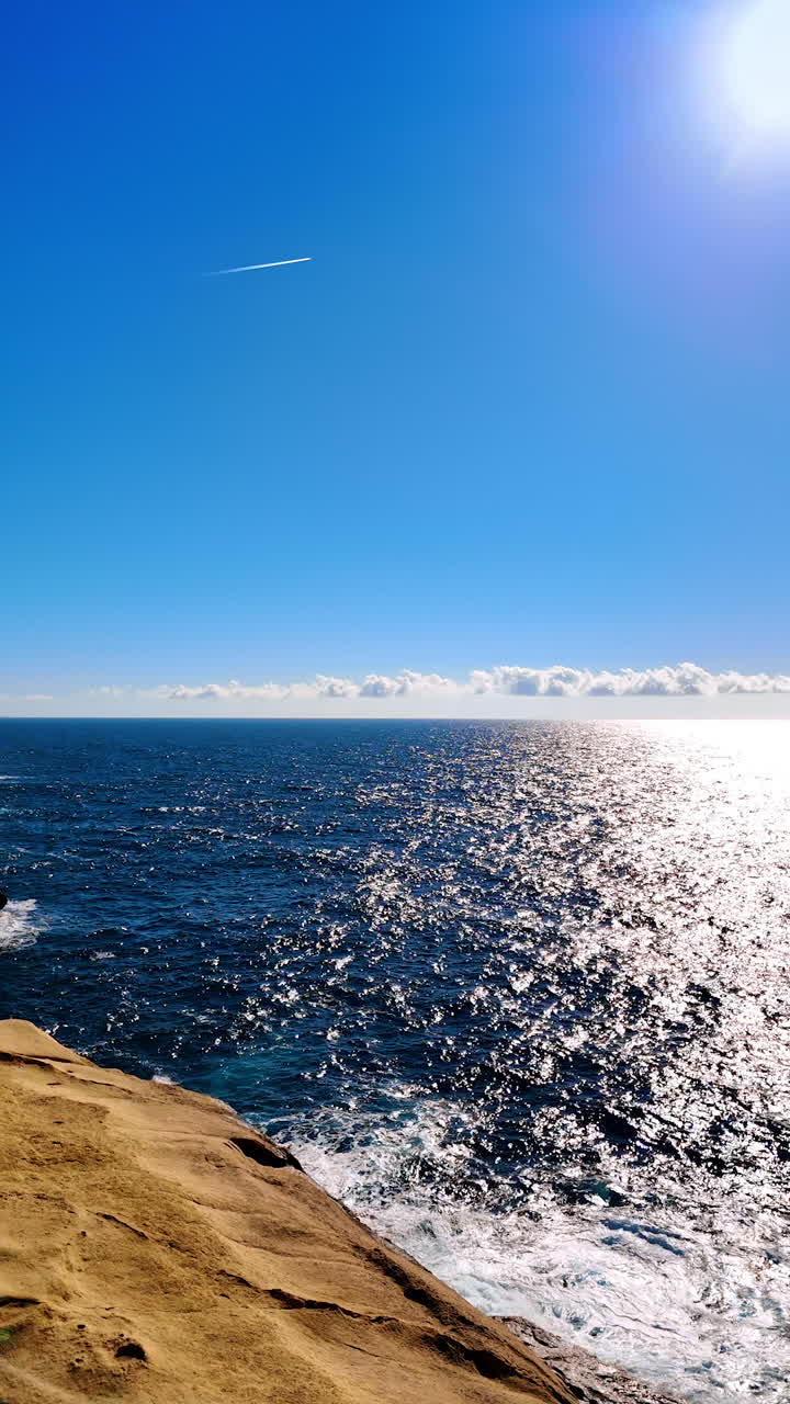 Tourists walk near the Xlendi Tower in Gozo Island, Malta. Rocky shore and blue waterscape of the Mediterranean Sea. Vertical video.