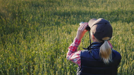 Eine-Frau-Schaut-Durch-Ein-Fernglas,-Das-In-Der-Endlosen-Grünen-Wiese-Steht