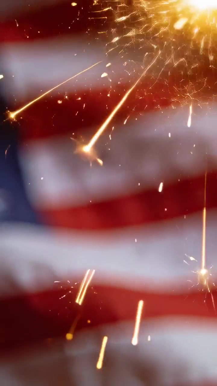 Vertical video: Sparking from ignition, embers streaking across blurred American flag in studio