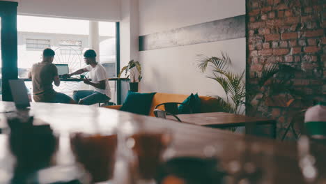 two young men working on a laptop in a coffee shop