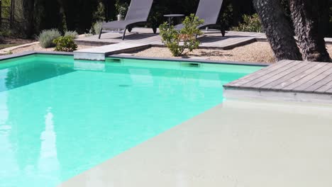 slow tilting shot revealing sun loungers sitting at poolside at a villa in nimes