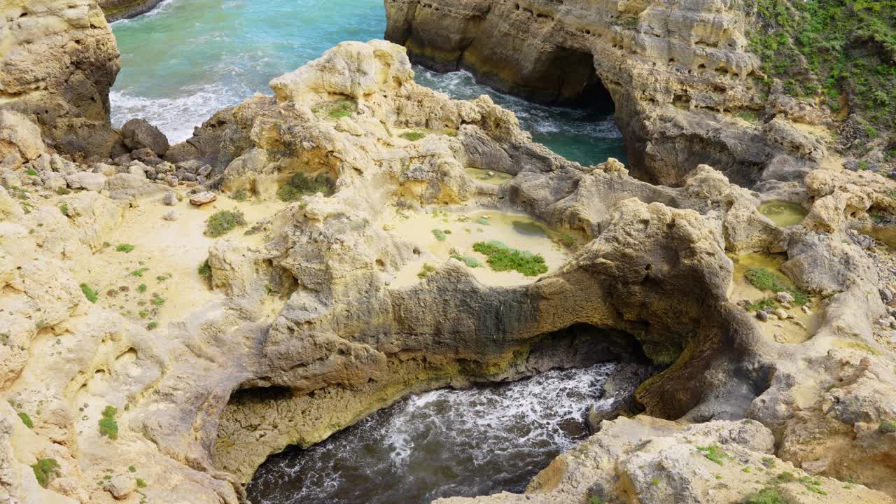 Waves Crashing On Rock Cliffs And Cave Holes In Algarve, Portugal. High Angle Shot