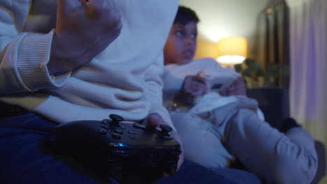 Nahaufnahme-Der-Hände-Von-Zwei-Kleinen-Jungen-Zu-Hause,-Die-Spät-In-Der-Nacht-Mit-Einer-Computerspielkonsole-Im-Fernsehen-Spielen-Und-Controller-Halten-8