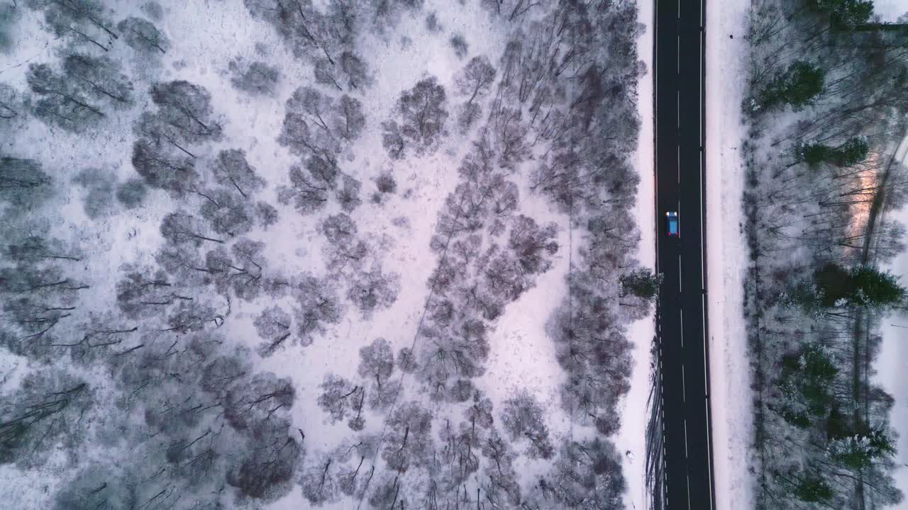 Inquadratura panoramica dall'alto di auto che guidano su una strada in un paesaggio invernale.