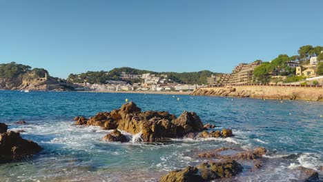 rocks in the foreground with the bay of tossa de mar in the background castle and walled enclosure