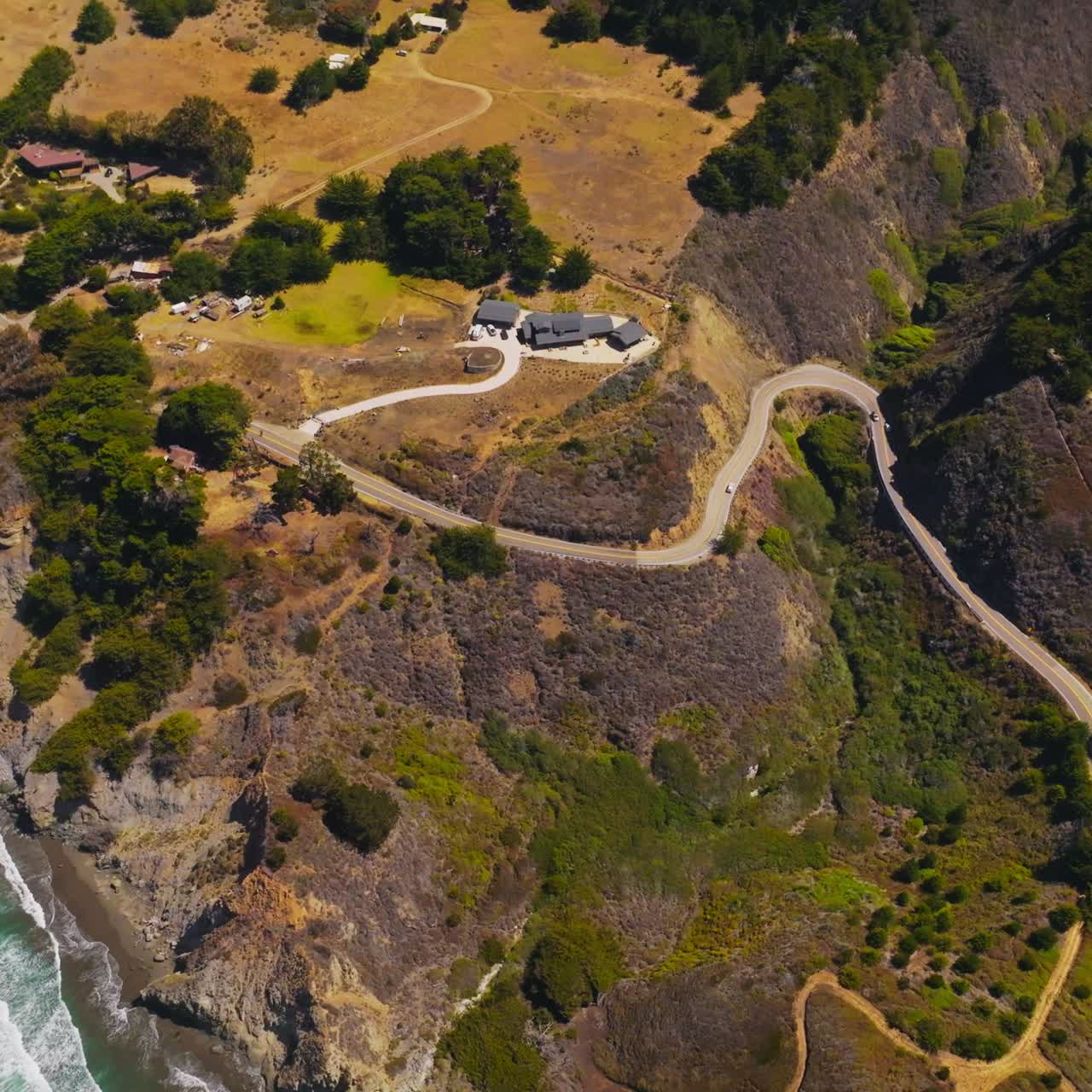 Stunning view of mountainous landscape of the ocean shore at Morro Bay, California, USA. Few houses and winding highway on the rocky coastline from aerial view