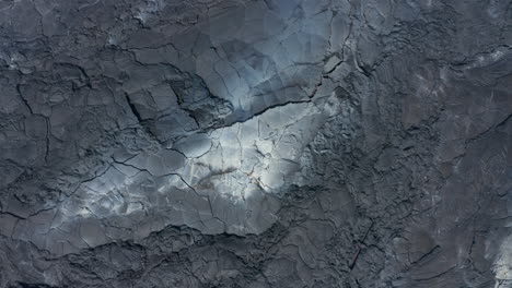 Aerial-birds-eye-overhead-top-down-view-of-volcanic-black-lava-lake-texture-in-Fagradalsfjall,-Iceland,-rising-up,-day