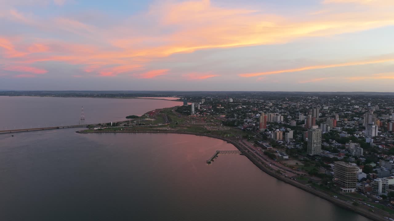 Coastal aerial skyline of high-rise buildings along a riverbank at sunset with pastel colors, Posadas, Misiones, Argentina.
