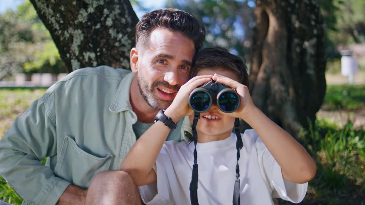 Little boy looking binoculars forest having outdoor adventure with daddy closeup