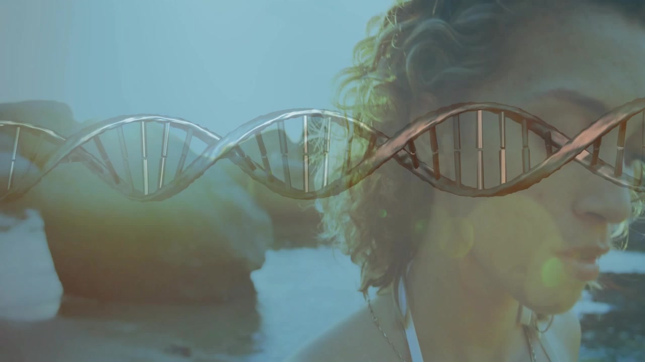Video verticale: Elica di DNA in movimento con una donna che si gira a destra su una costa rocciosa, spalline del bikini visibili.