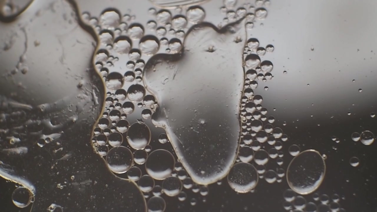 Gocce d'olio e forme astratte che galleggiano nell'acqua, macro