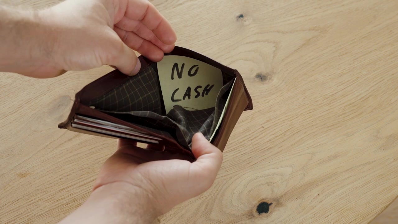 Un hombre abre su cartera y encuentra una nota que dice "Sin efectivo" en lugar de dinero. Concepto de apuros económicos, cartera vacía, presupuestación y falta de efectivo.