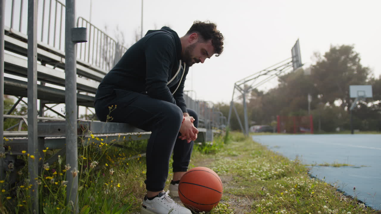 Tired Man Rests After a Tough Basketball Game in the Park