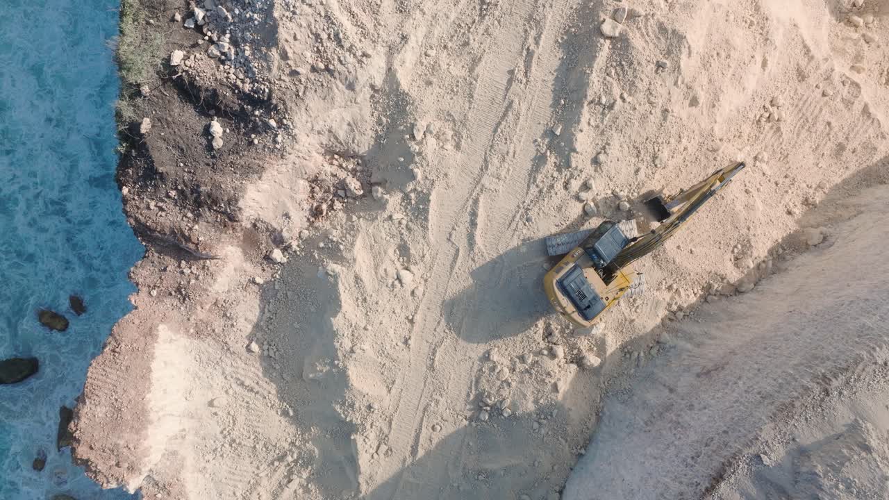 Top Down Drone Video of Turquoise Waves Crashing Against Environmental Destruction of the Limestone Cliffs near Pura Luhur Uluwatu Temple, Bali Indonesia with Massive Earth Clearing
