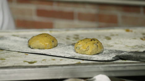 panadero colocando masa de galleta de pan de pasas cepillada con huevo lavado sobre una cáscara para hornear - primer plano