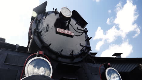 historic steam locomotive with license plate and lights on sunny day and clouds passing by, time lapse