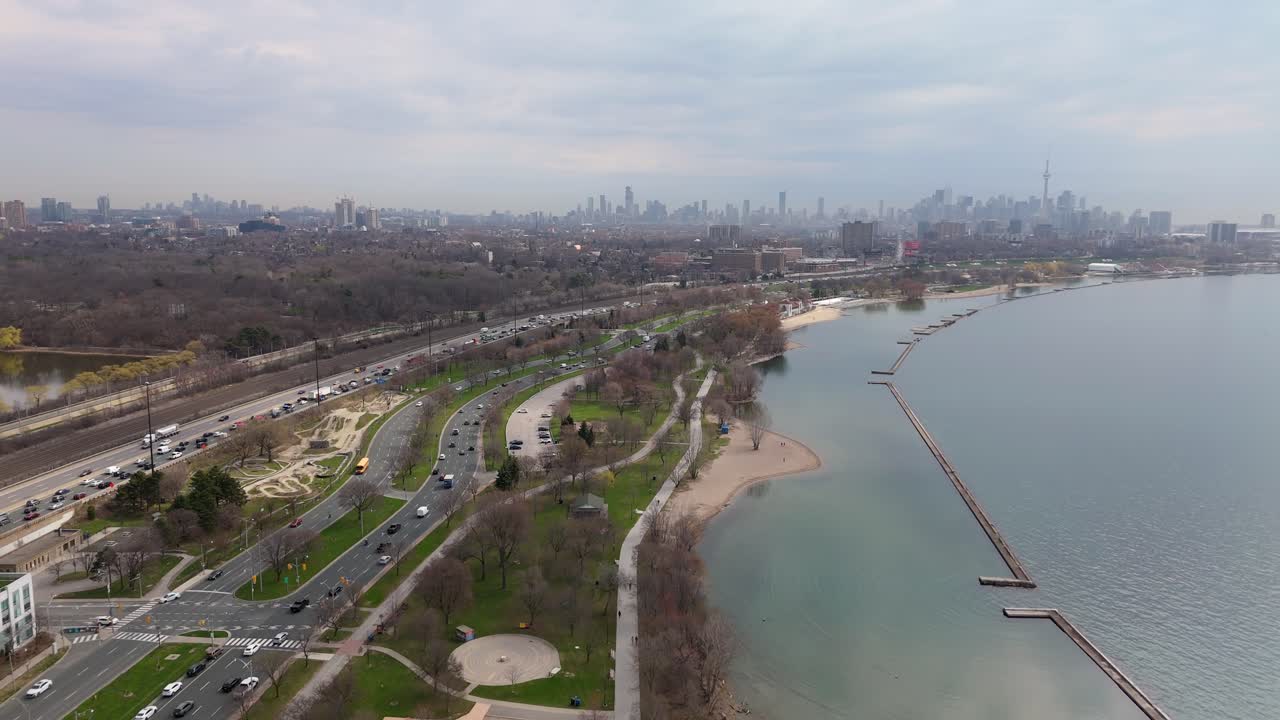 Condo towers line Lake Ontario along Lakeshore Blvd in Toronto with downtown skyline visible, aerial establishing