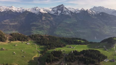 Bird's-eye-view-of-the-marvelous-Amden-Arvenbüel-valley,-with-snowy-mountains-in-the-background