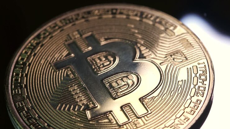 Criptomoneta 4K in valuta Bitcoin che ruota lentamente in senso orario con luce riflessa su sfondo nero