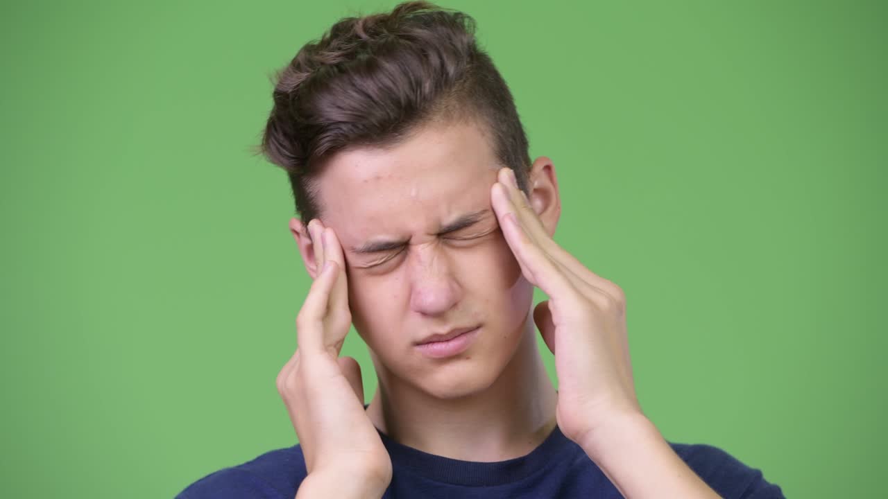 Young handsome teenage boy having headache