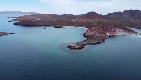 Vista-Aérea-Panorámica-De-La-Hermosa-Playa-Pichilingue-Cerca-De-La-Paz-En-Baja-California-Sur-México-Con-Mar-Azul-Con-Barcos-Flotantes-Y-Paisaje-Rocoso-Con-Montañas-En-El-Fondo