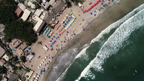 birds eye aerial view of beach, ocean waves, parasols