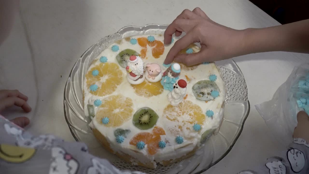 행복한 가족, 어머니와 딸, 하 크림과 산타클로스와 동물의 과일 동상으로 크리스마스 케이크를 장식하십시오.